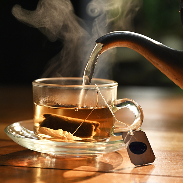 hot water pouring into transparent cup with tea bag