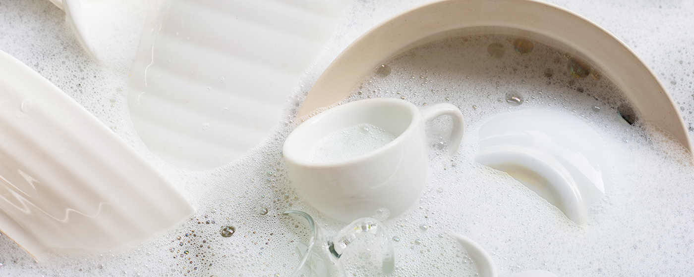 Washing dishes, Close up of utensils soaking in kitchen sink.