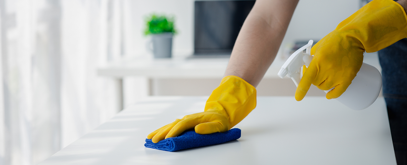 Person cleaning the room, cleaning staff is using cloth and spra