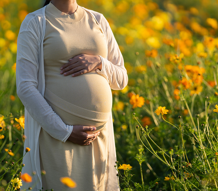 Pregnant woman is relaxing in the flower garden.