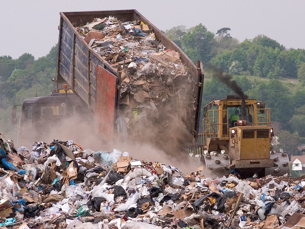 A bulldozer and garbage truck on a landfill waste site
