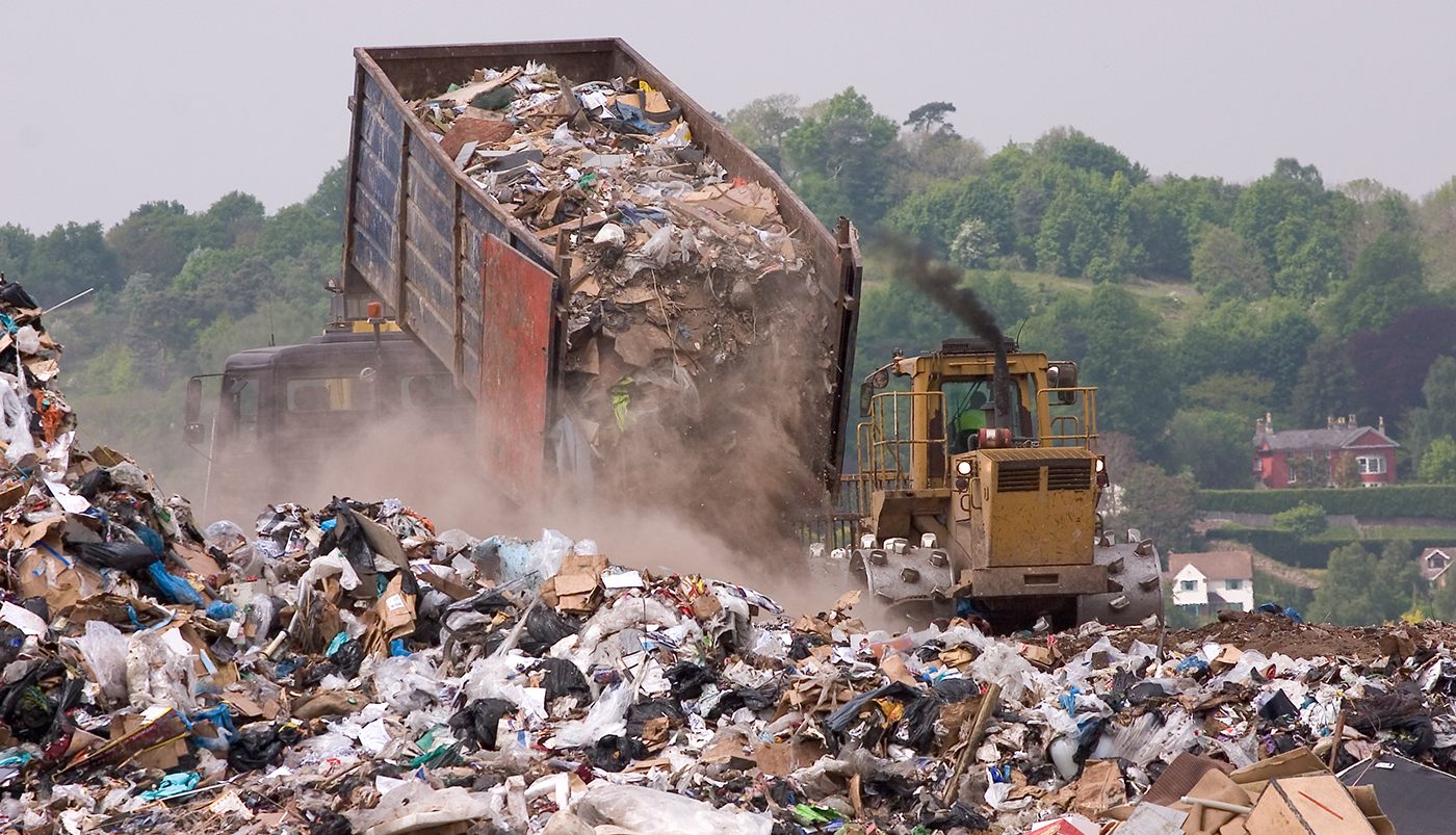 A bulldozer and garbage truck on a landfill waste site