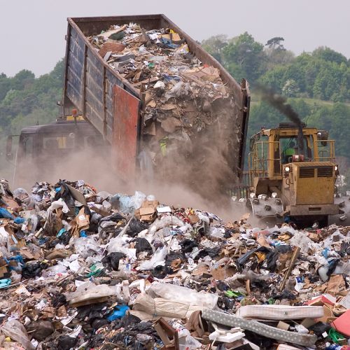 A bulldozer and garbage truck on a landfill waste site